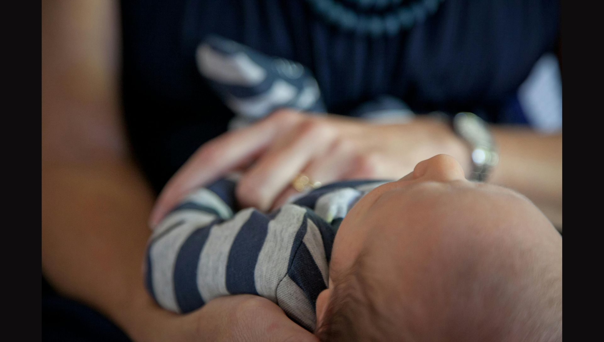 Female in Blue Top Holding Baby in Blue and Gray Stripe Top (Image via Pexels)