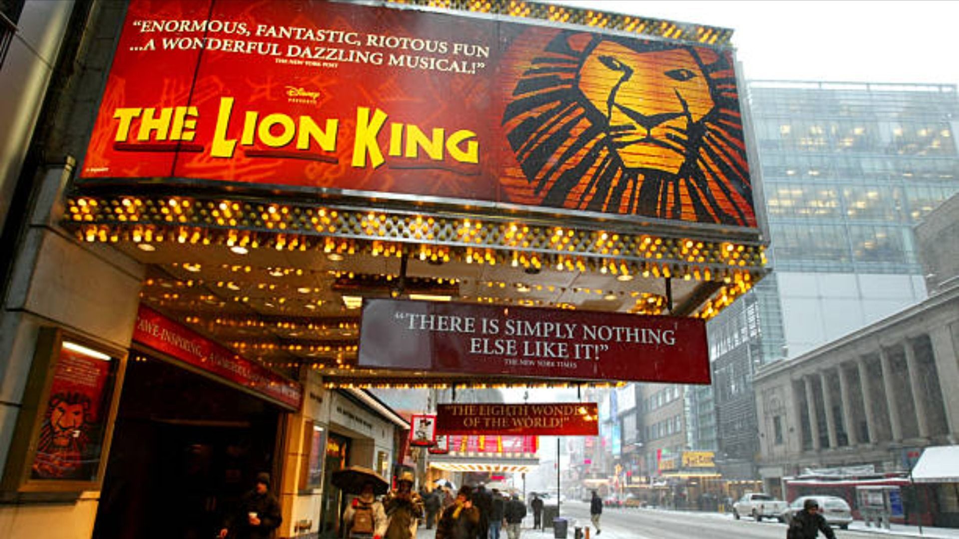 Pedestrians walk beneath a sign for the musical 