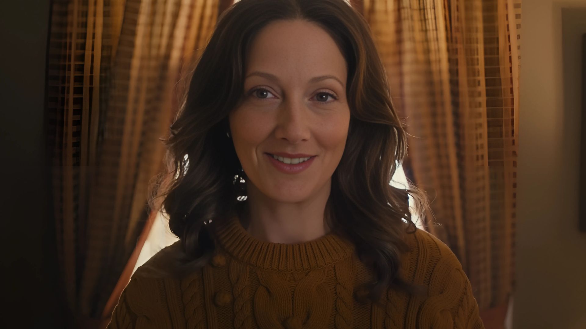 Judy Greer is seen smiling with curtains in the background