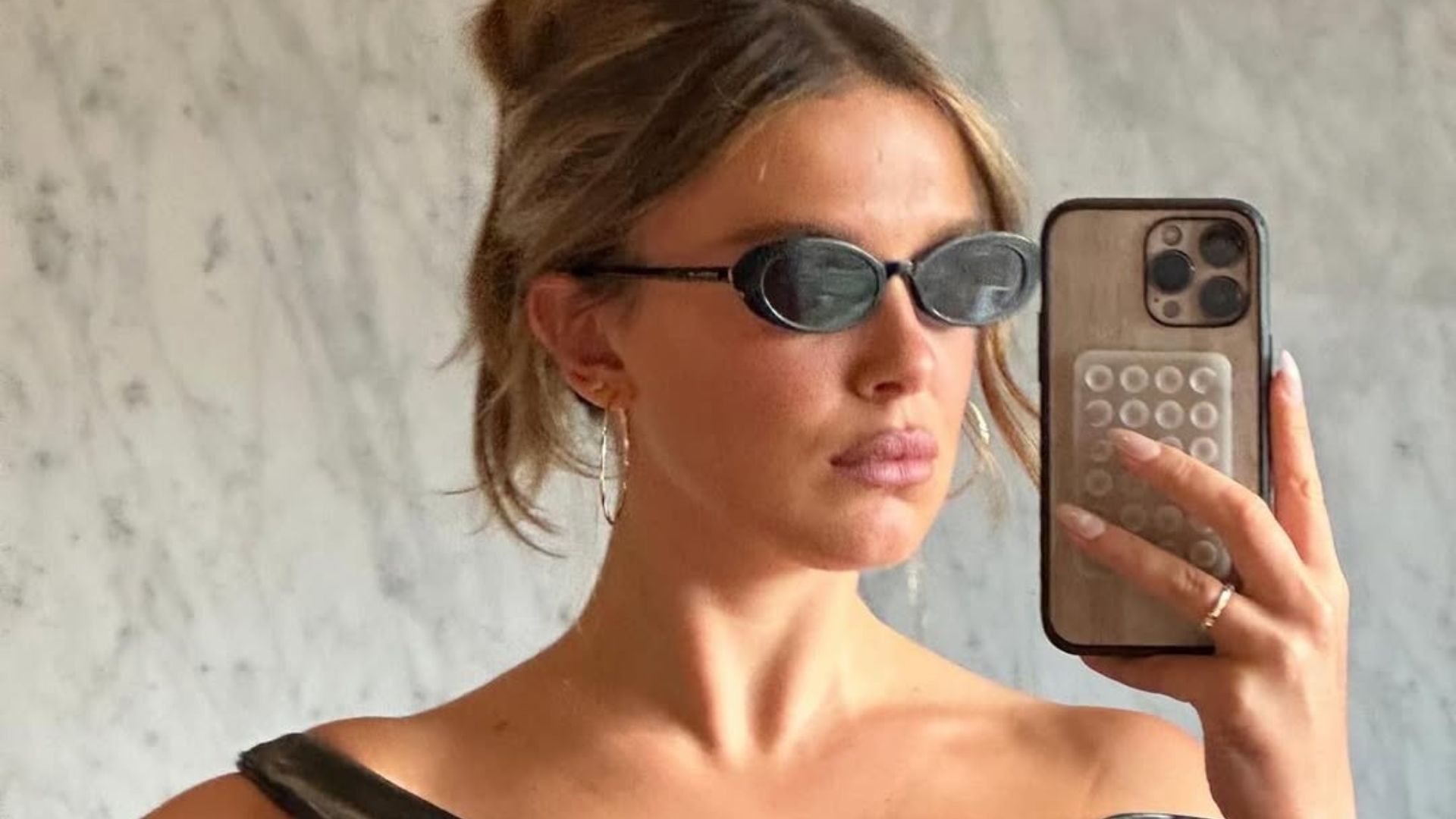 Millie Bobby Brown Bongiovi shared a selfie on Instagram on January 22, 2025, wearing a black leather asymmetrical top and dark shades (Image via Instagram/@milliebobbybrown)