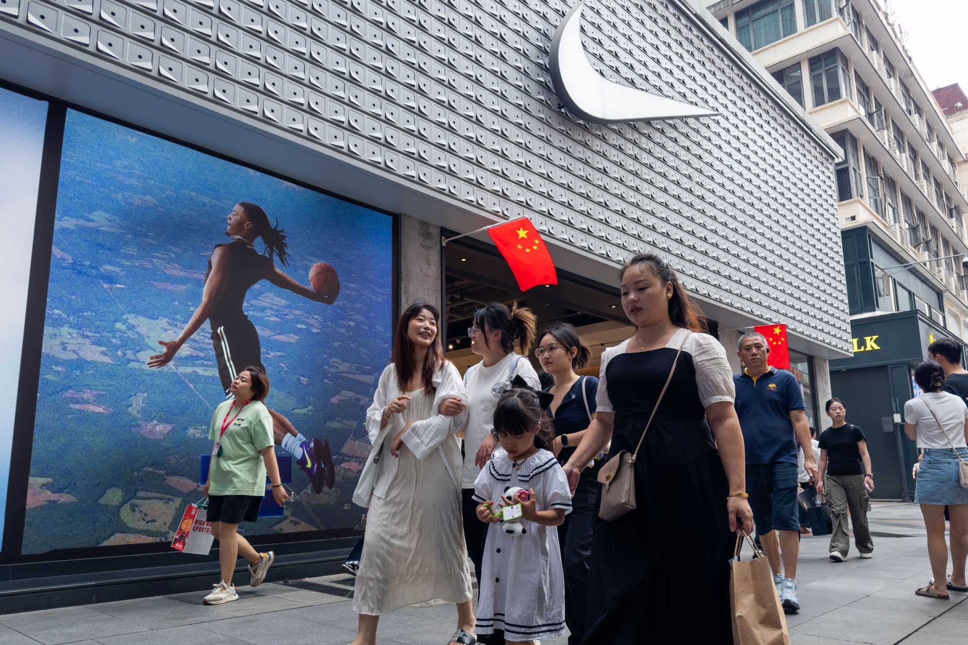 Shoppers Walk Past Nike Storefront Decorated for National Day in Chengdu - Source: Getty