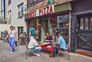 Patrons share and enjoy a pizza outside at Best Pizza in Brookl - Source: Getty