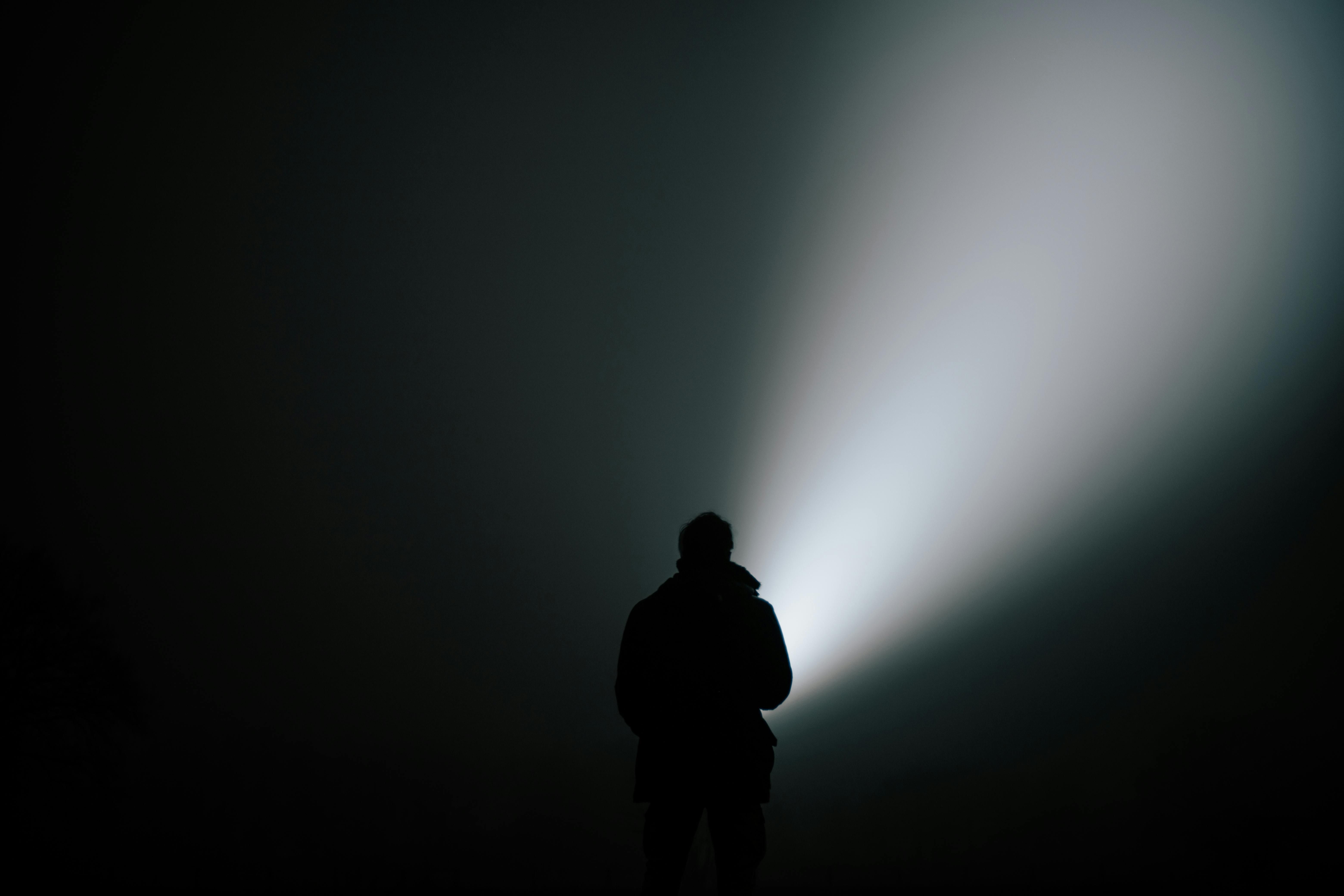 Silhouette in Dense Fog with Flashlight (Image via Pexels)