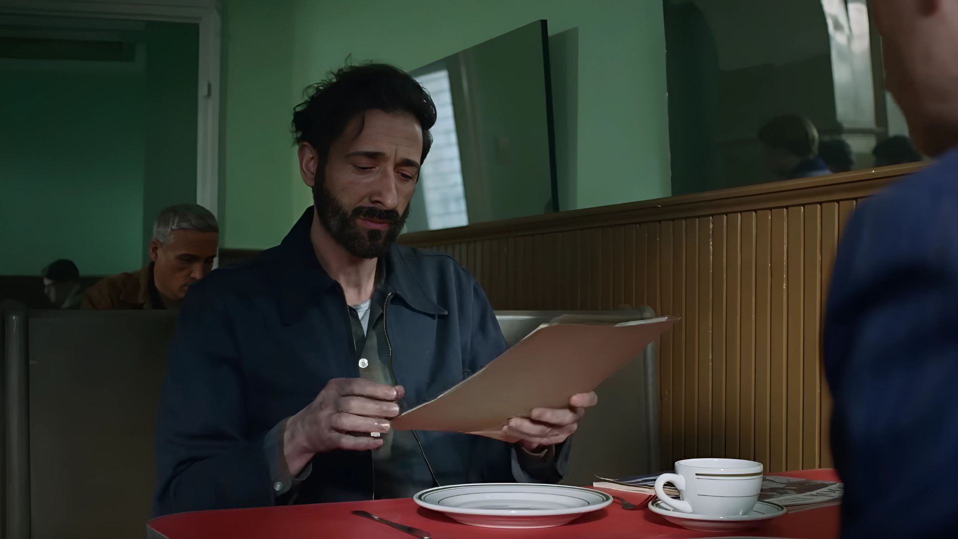 Adrien Brody reads something in The Brutalist