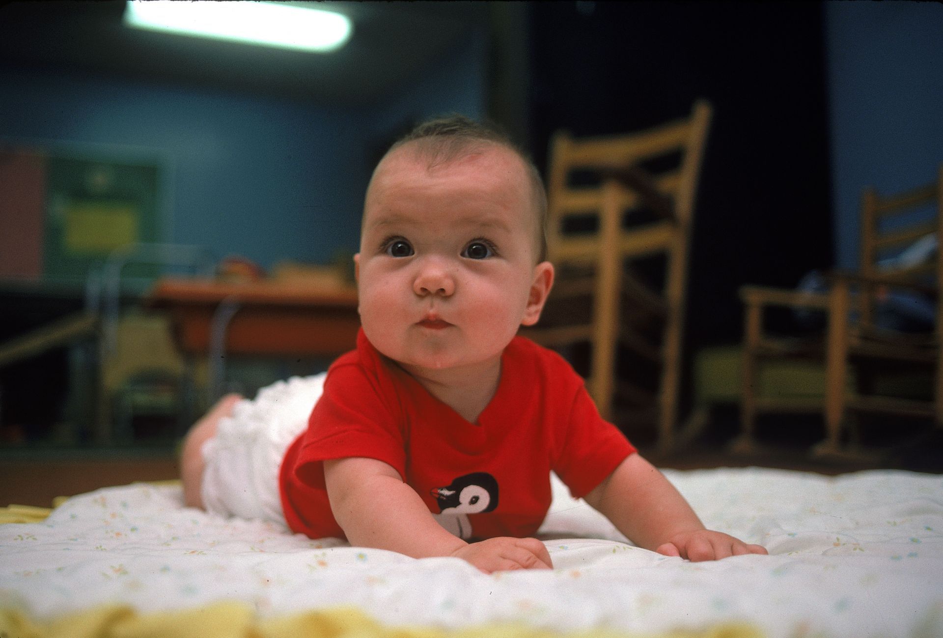 A cute wide-eyed infant perking head up on blanket on - Source: Getty