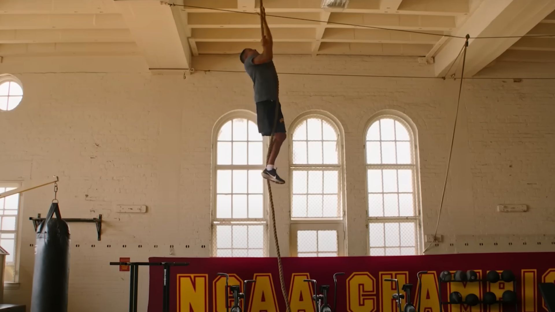 A man climbing rope in a gym