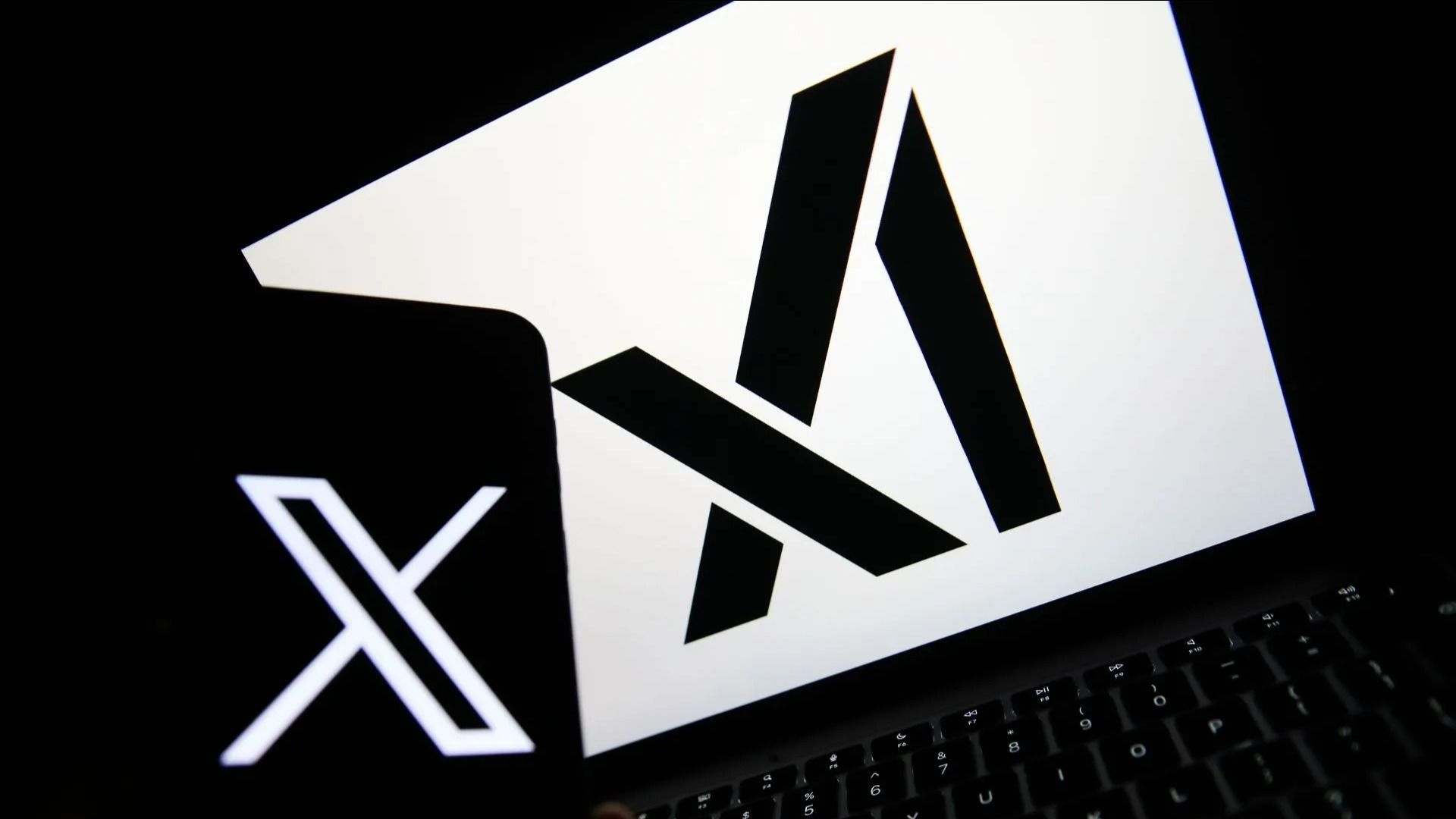 The X logo appears on a phone, and the xAI logo is displayed on a laptop - Source: Getty