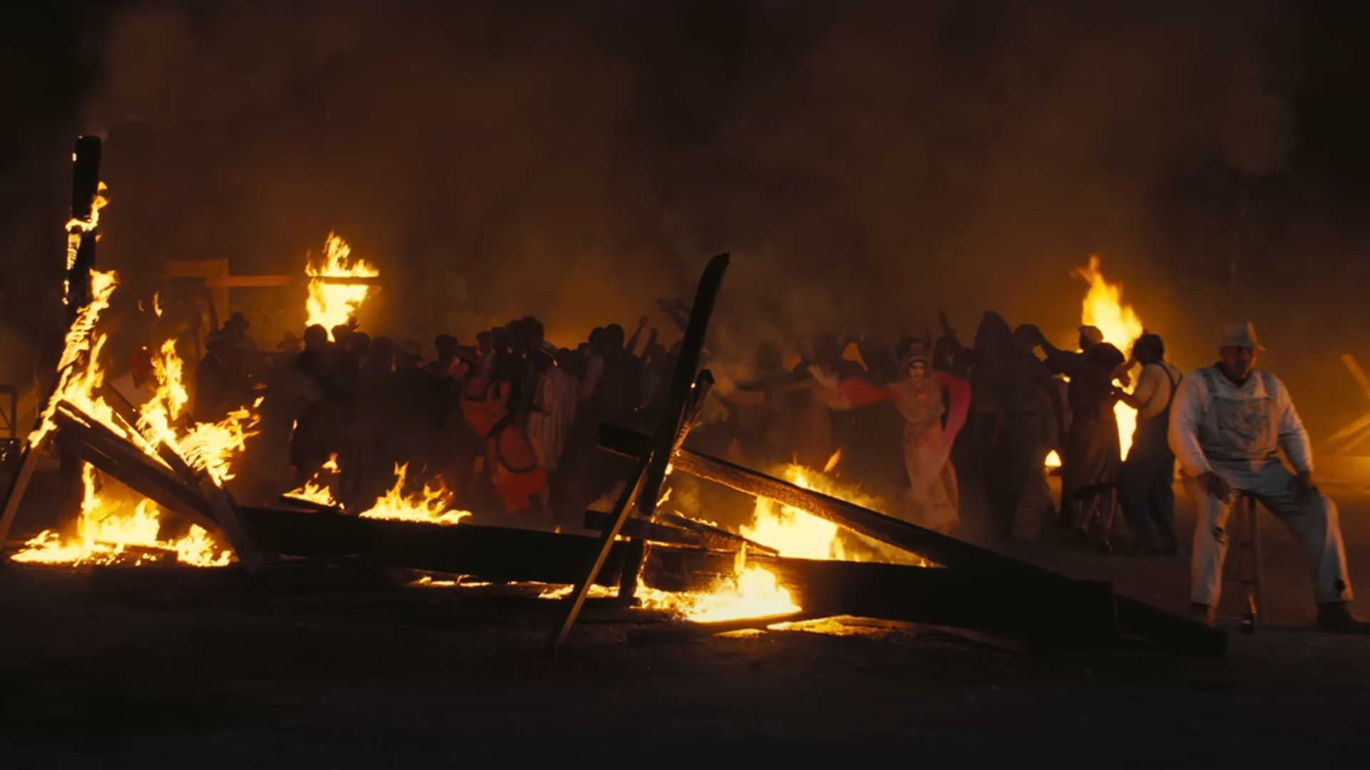 People appears to be fighting around fallen wooden structure that