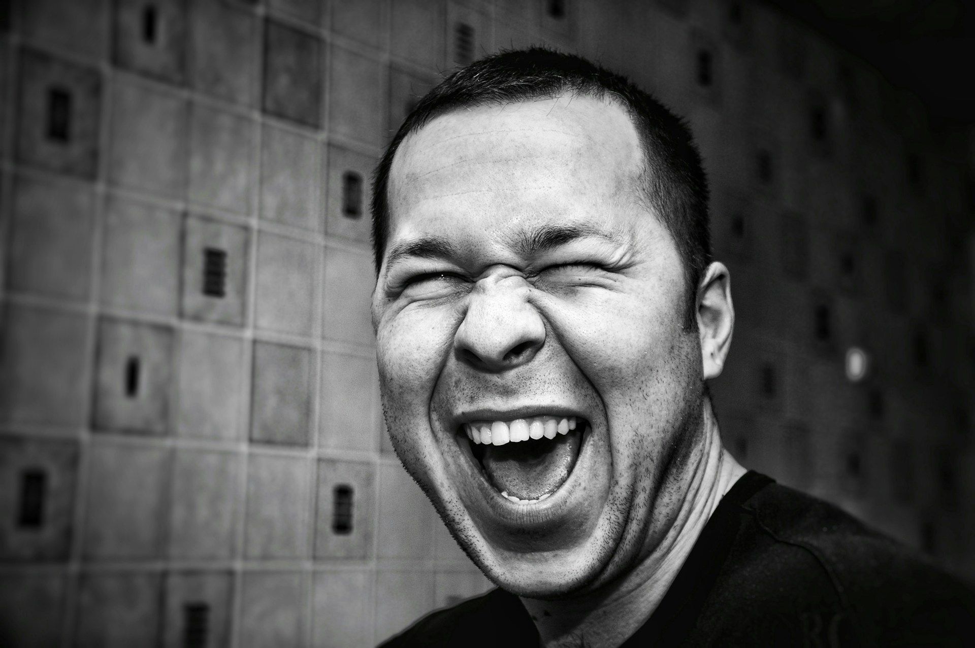 A man laughing black and white picture (Image via Unsplash/Denis Agati)
