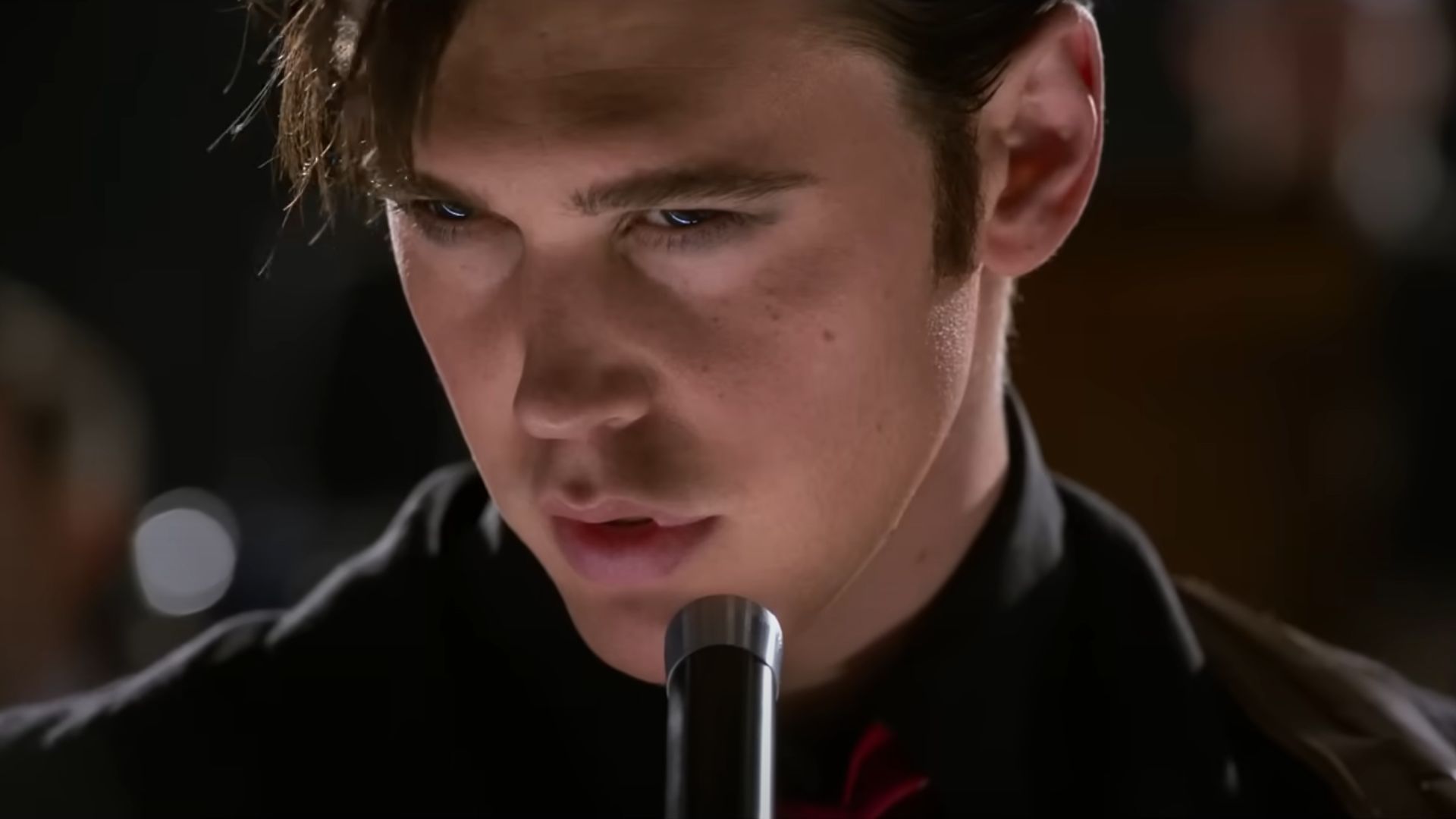 Austin Butler as Elvis wearing black with a mic in front of him