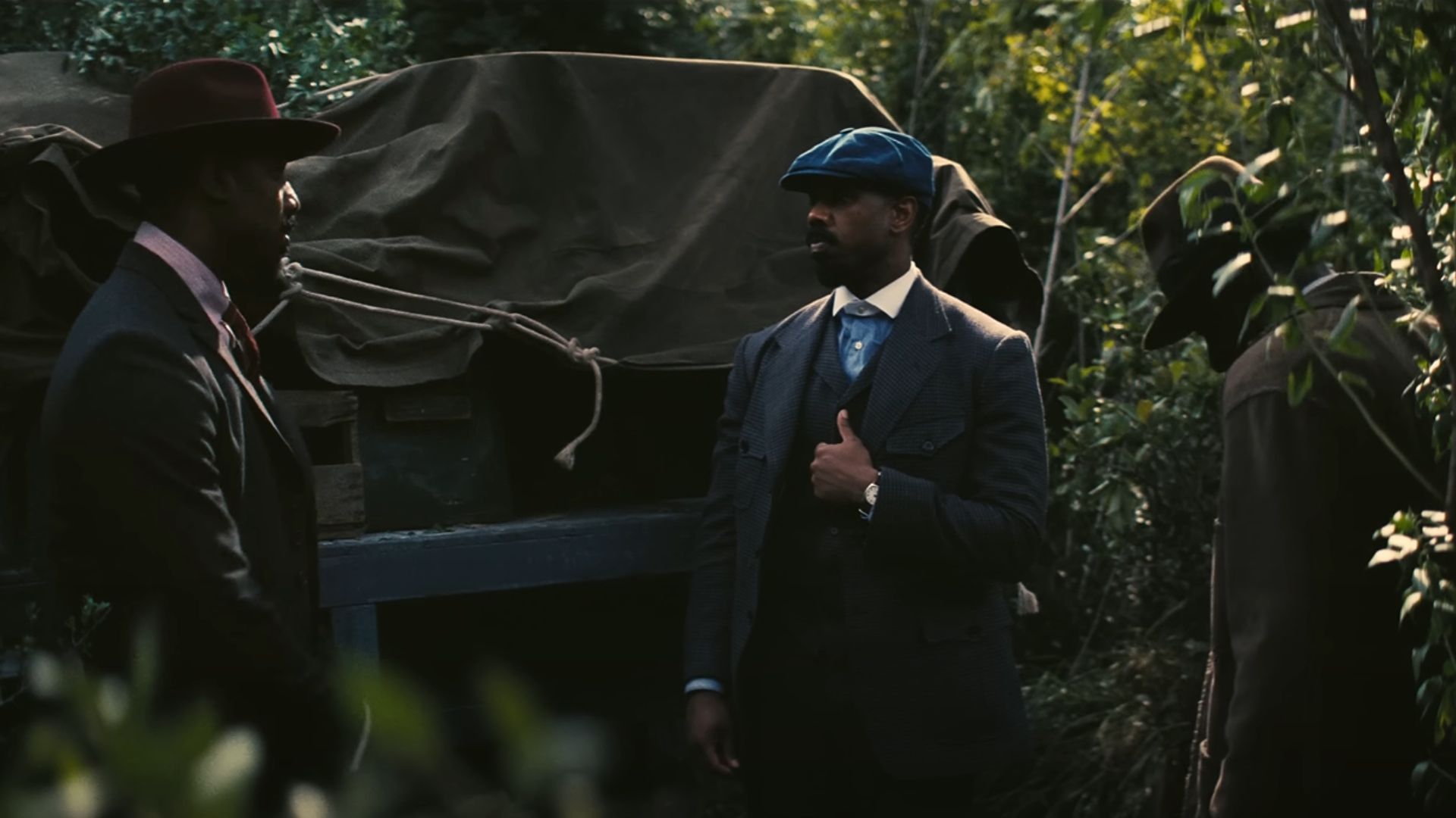 Three well dressed men stand in a jungle