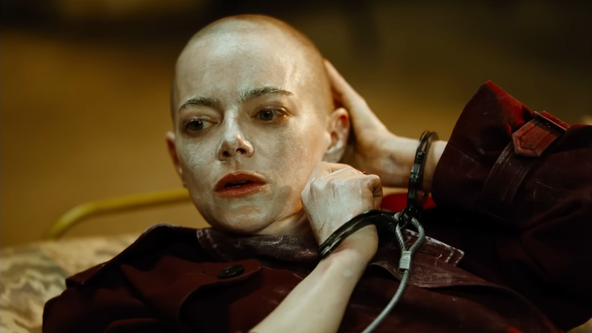 Emma Stone with a shaved head and a cream rubbed all over her face and head.